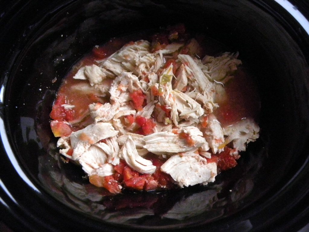 shredded chunks of chicken in a diced tomato sauce in a crock pot