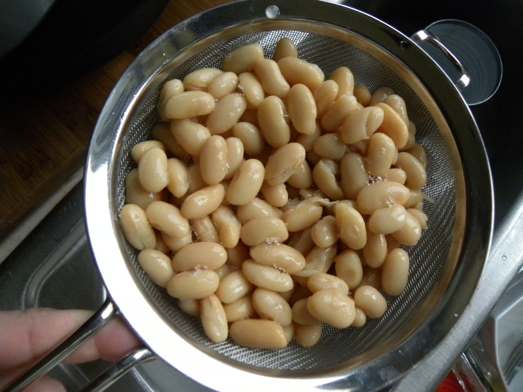 straining juices of beans over a sink