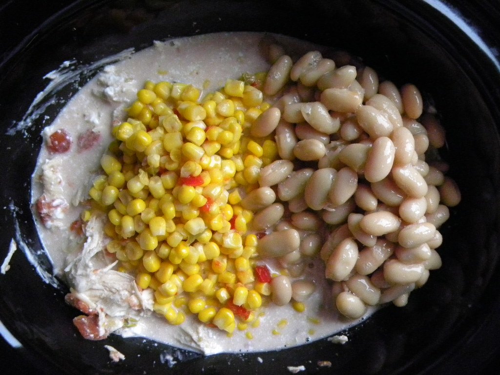 black crock pot with chicken and diced tomato mixture with beans and corn on top