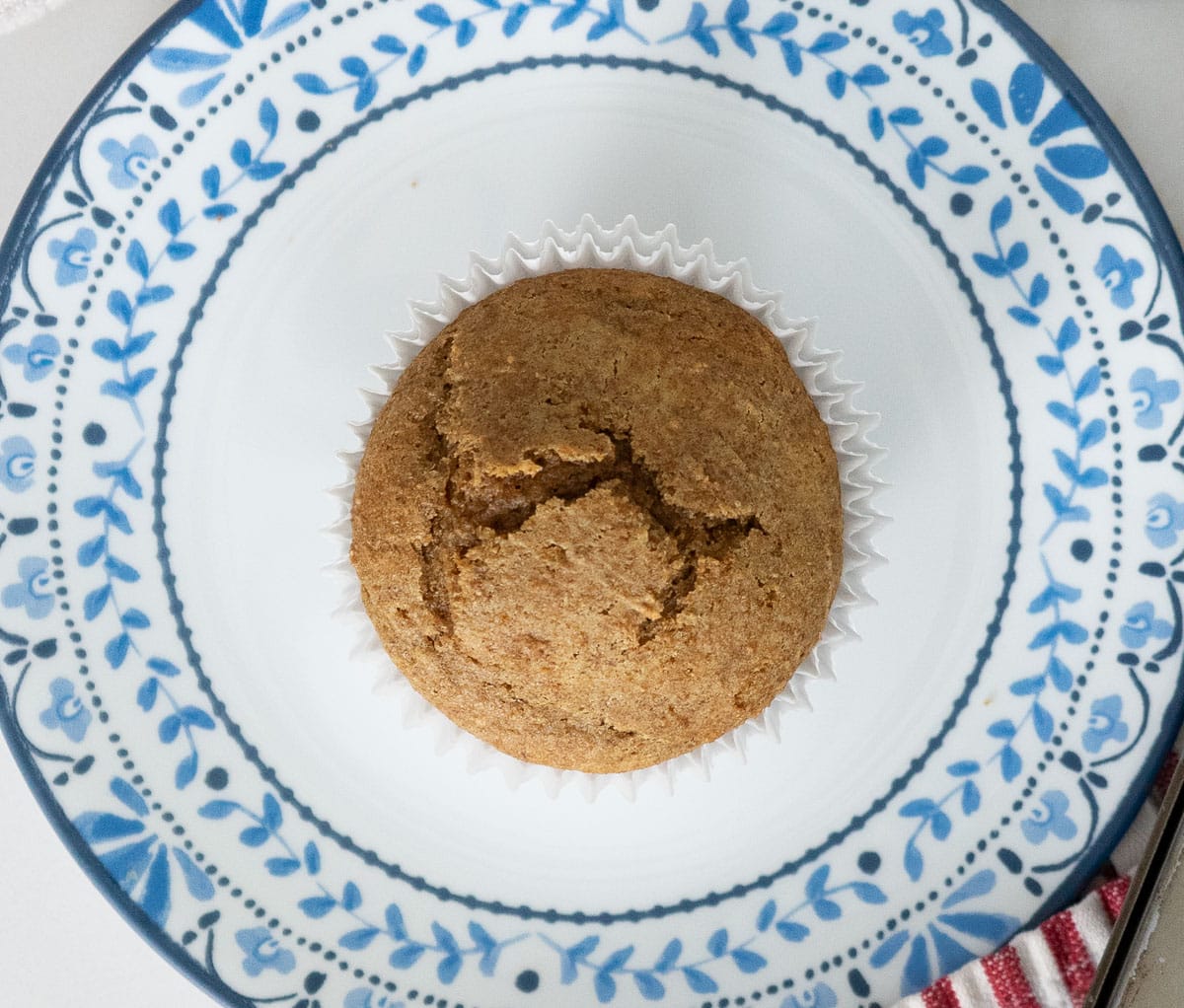 one bran muffin on a white plate trimmed with blue flowers