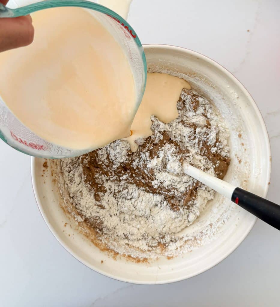 adding buttermilk to the bran muffin batter in the large bowl on a white countertop