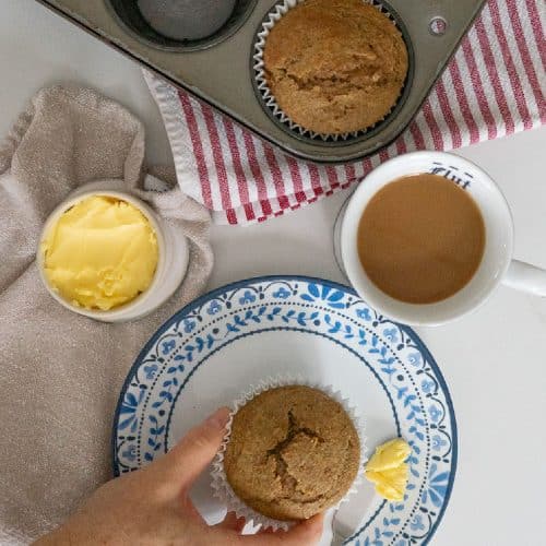 top photo has muffin tin with baked muffins in it, a crock of butter, a cup of coffee and then a whole bran muffin is sitting on a white plate with blue flowers around the edge with a butter knife with butter on it laying beside the muffin