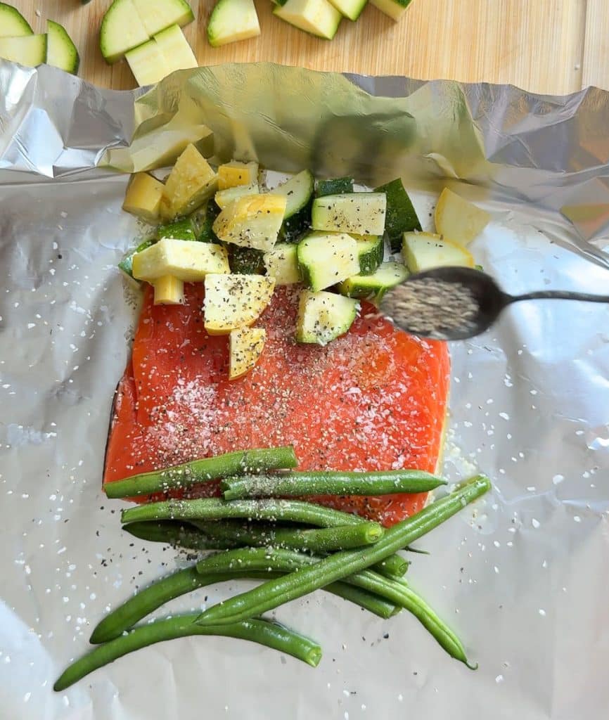 DSCN6712 sprinkling salt and pepper over salmon fillet and vegetables on aluminum foil