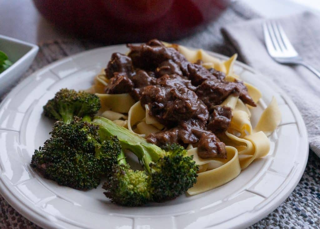 DSCN6284 plate of no peek beef tips on top of noodles with broccoli red pot in the background