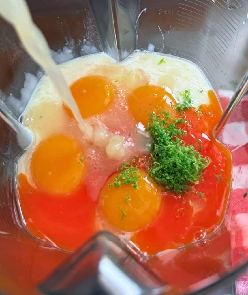 all of the ingredients added to the bowl of my blender, key lime juice is being poured into the pitcher from the left side. 