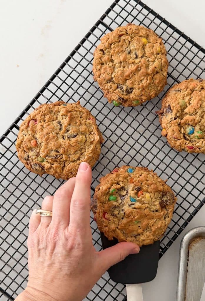 hand picking up a cookie off the cooling rack