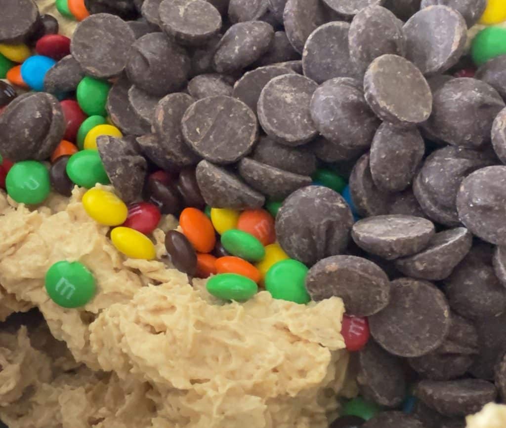 adding chocolate chips and m&m's to the cookie dough