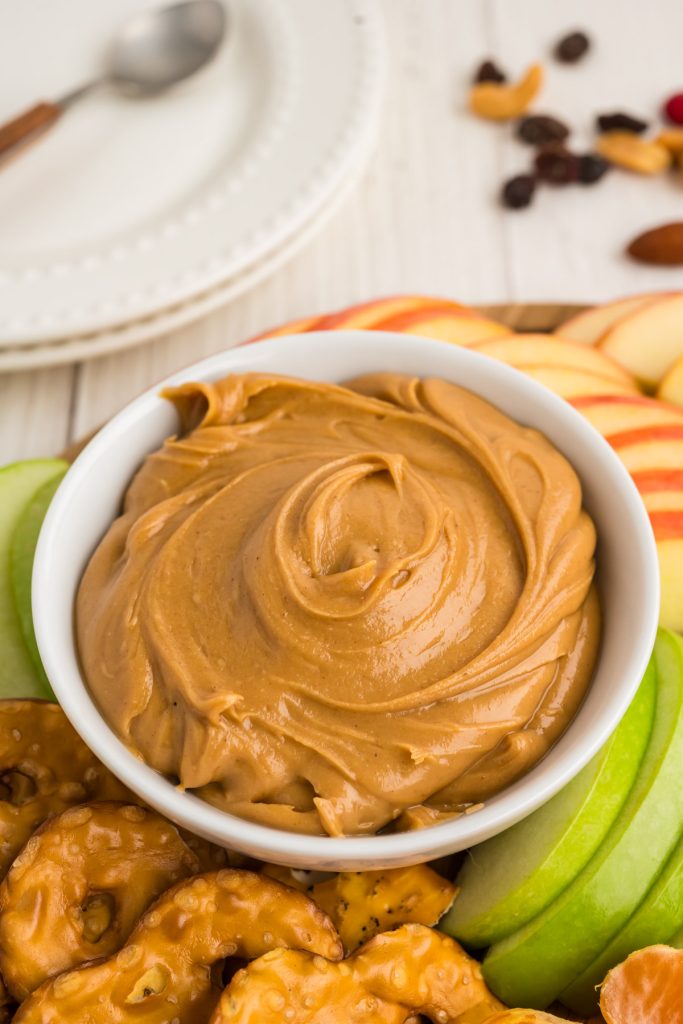 peanut butter honey spread in a white bowl surrounded by apples