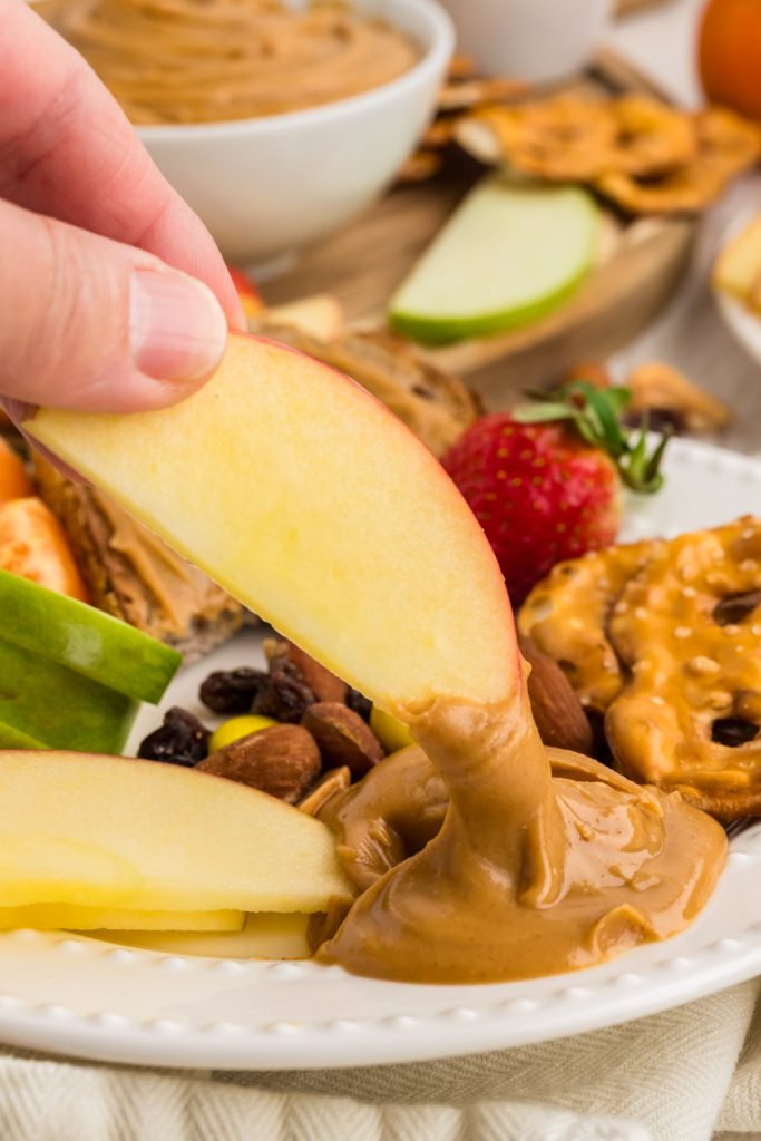 dipping apple slice in peanut butter honey spread