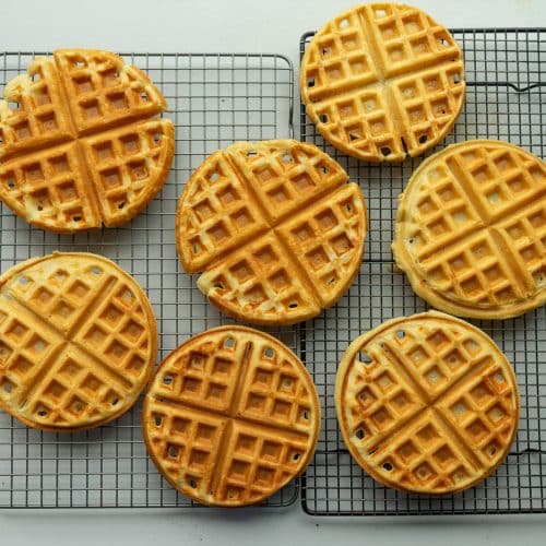 homemade waffles cooling on a wire rack on a white counter