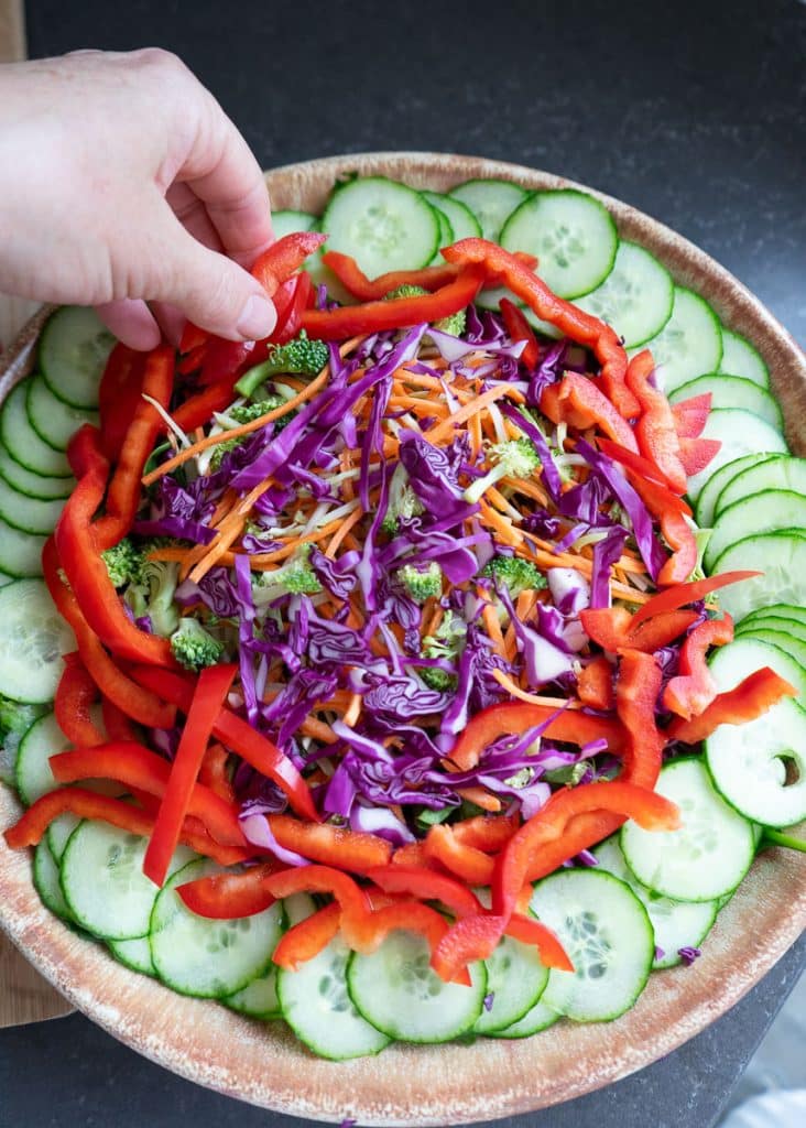 finishing salad with cucumbers red bell pepper and red cabbage