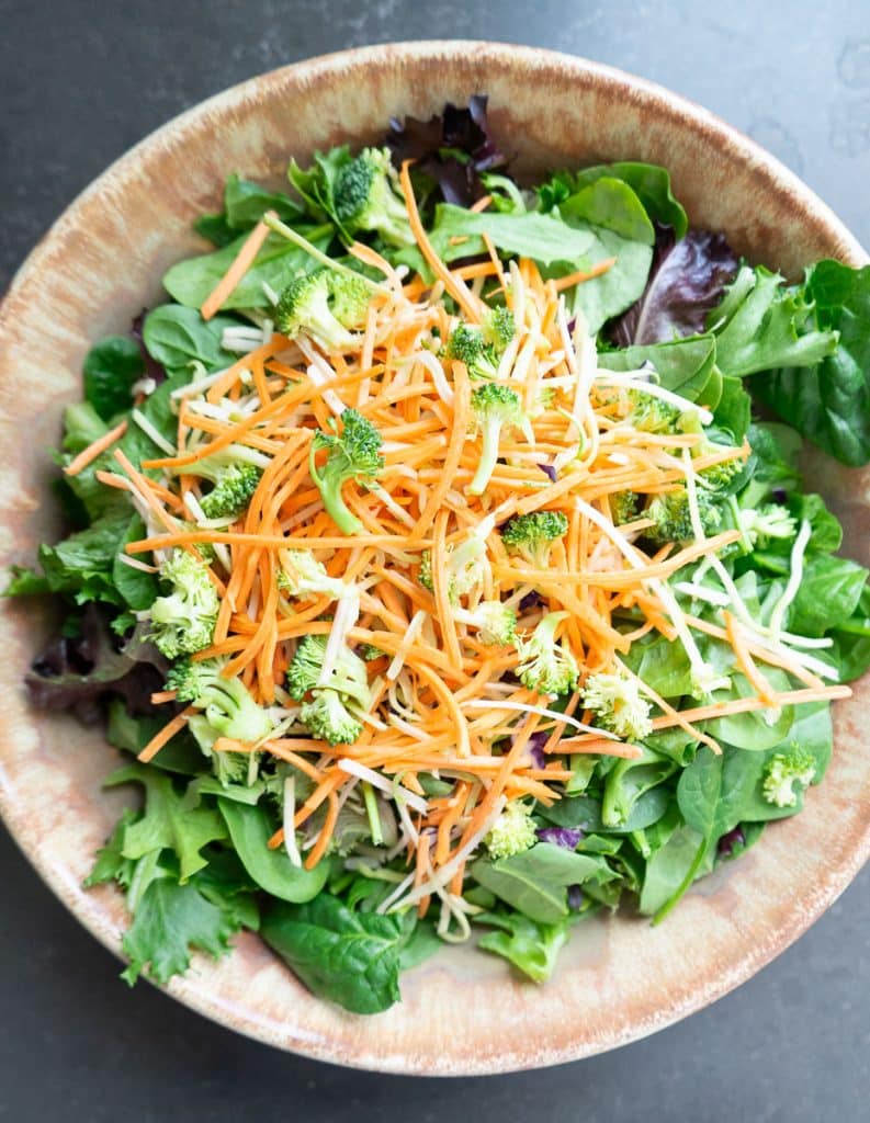 add broccoli slaw to mixed greens and spinach in salad bowl