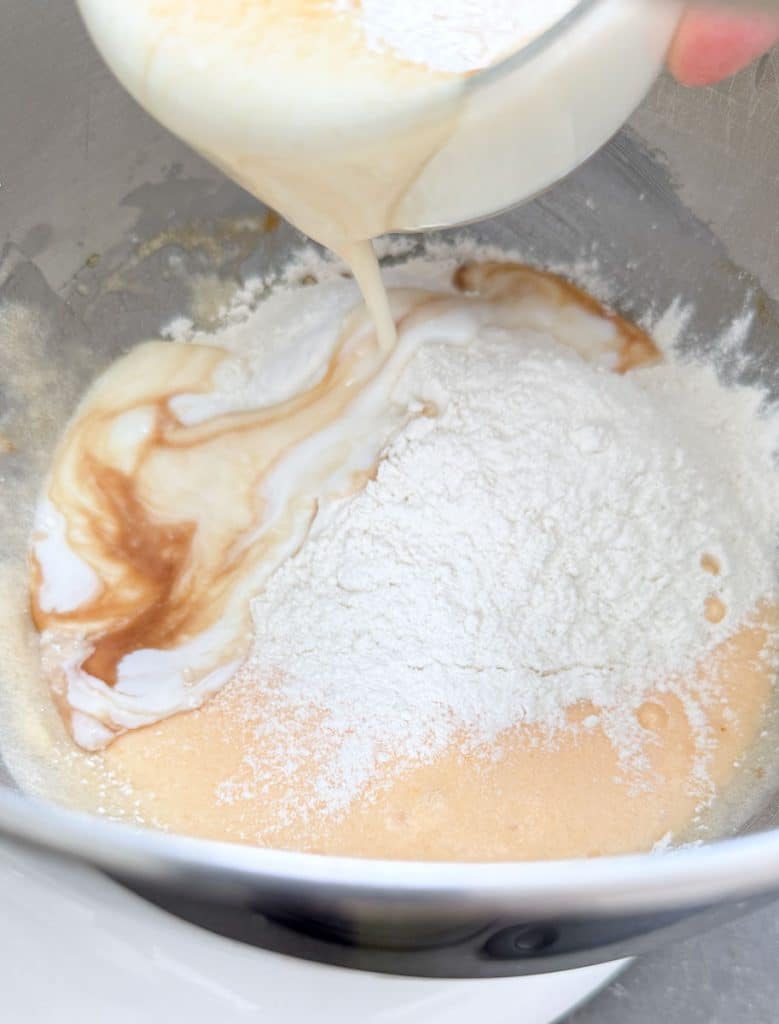 adding wet ingredients to dry ingredients in bowl of stand mixer