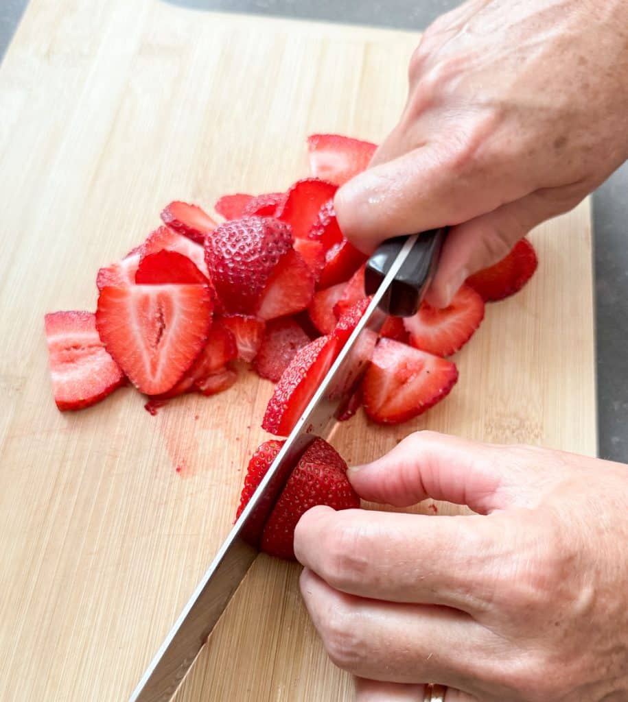 slicing strawberries on a wood cutting board
