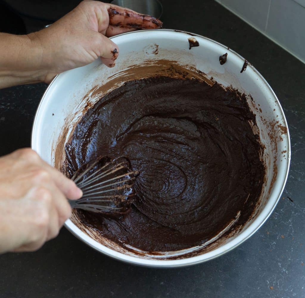 DSCN8286 whisking eggs, sugar, and cocoa powder together in a medium sized white bowl on a black countertop