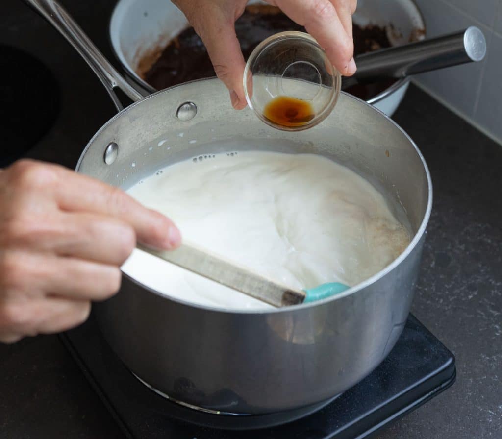 DSCN8291 cream in a sauce pan on burner stirring with a spatula and adding vanilla extract to the milk