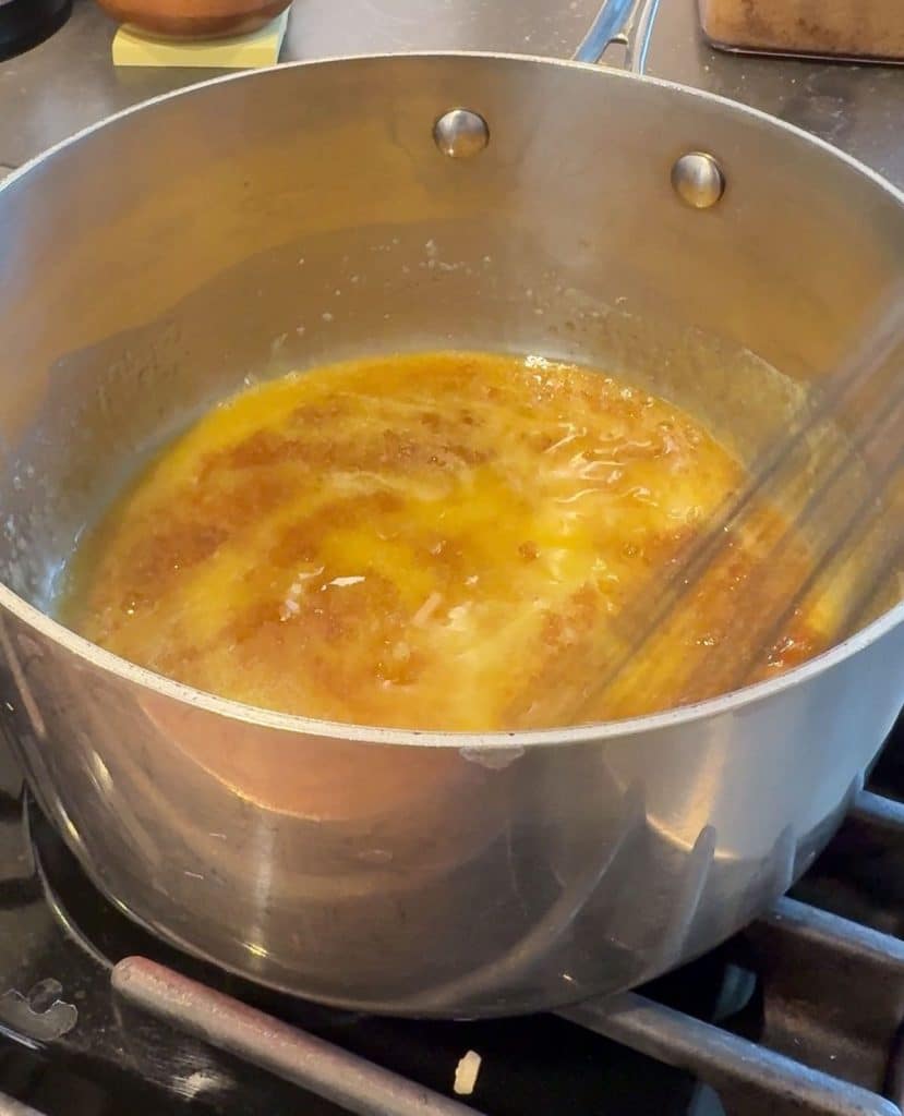 pan with melted butter and brown sugar in it on stovetop being whisked