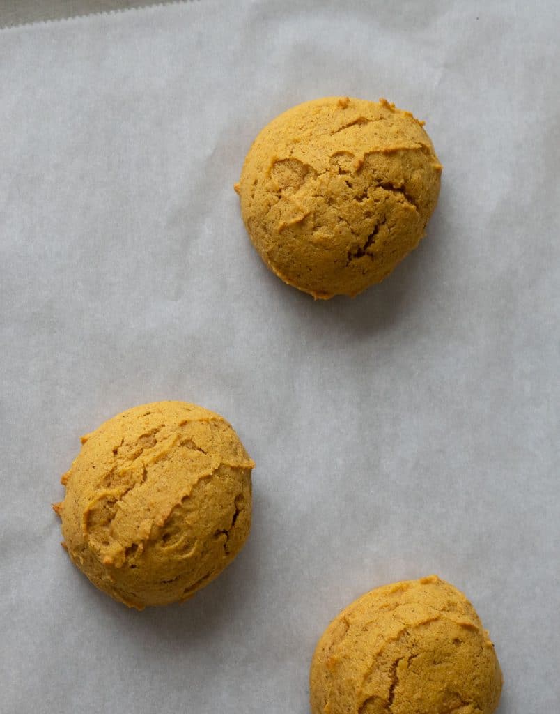 baked pumpkin spice cookies on parchment lined baking sheet