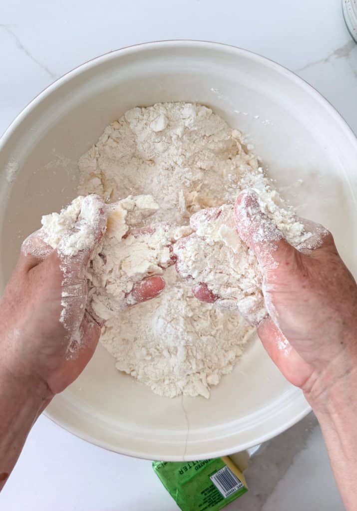 working butter and cream cheese into dry flour ingredients with hands