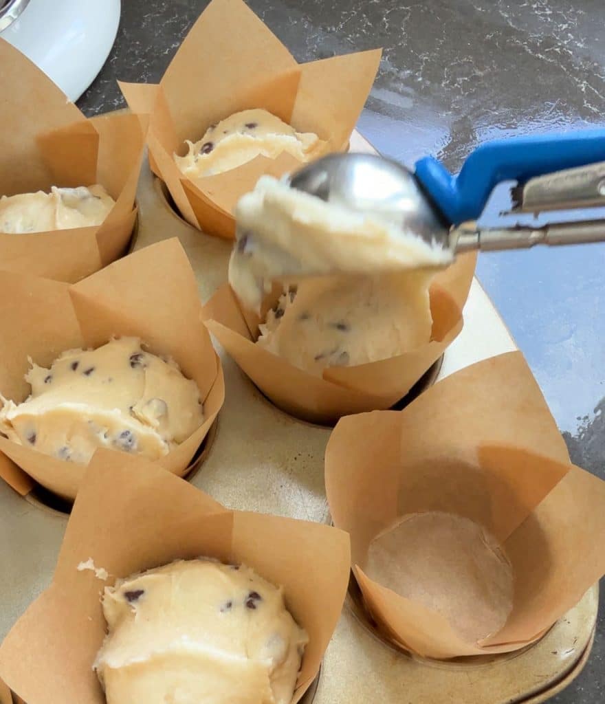 scooping muffin batter into muffin cups