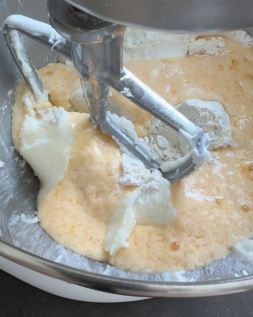 adding wet and dry ingredients to the creamed butter sugar in the bowl of a stand mixer