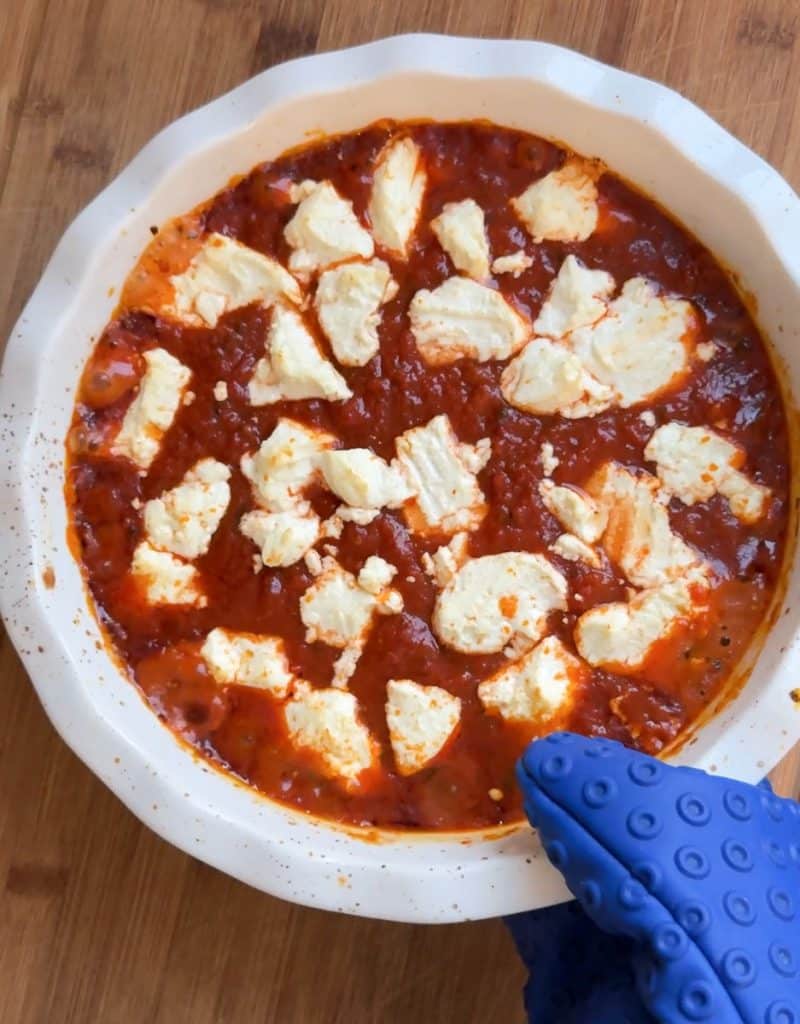 set freshly baked goat cheese dip on a wood serving board