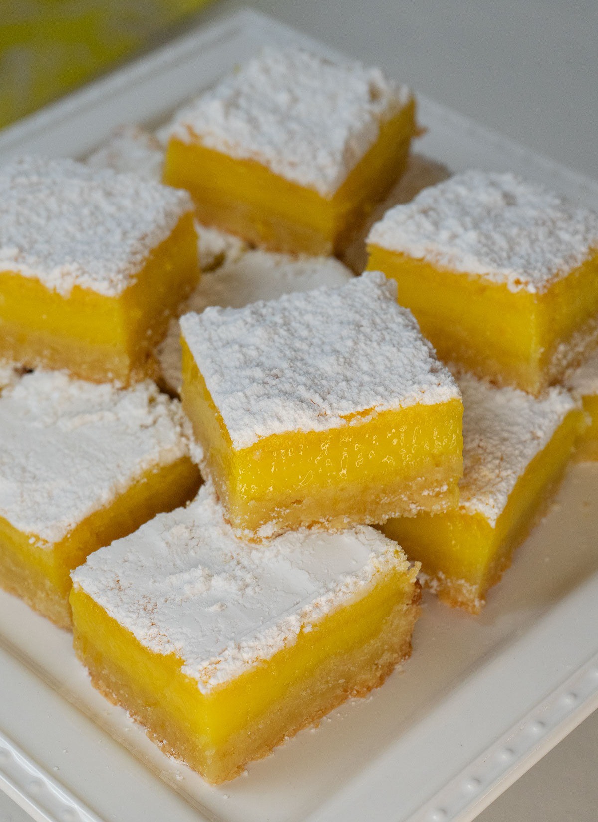 lemon bar squares stacked on a white platter
