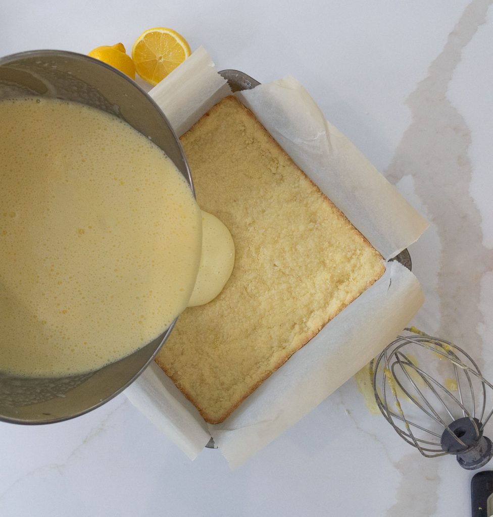 pouring lemon bar filling over par-baked crust 