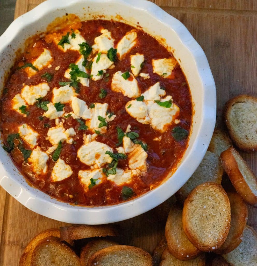 IMG_4264 white dish with marinara and goat cheese dip surrounded with crostini on a wood serving board