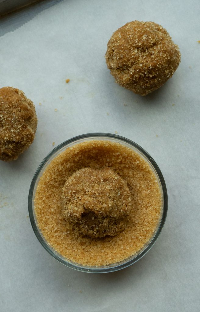 molasses cookie dough ball in bowl of turbinado sugar 
