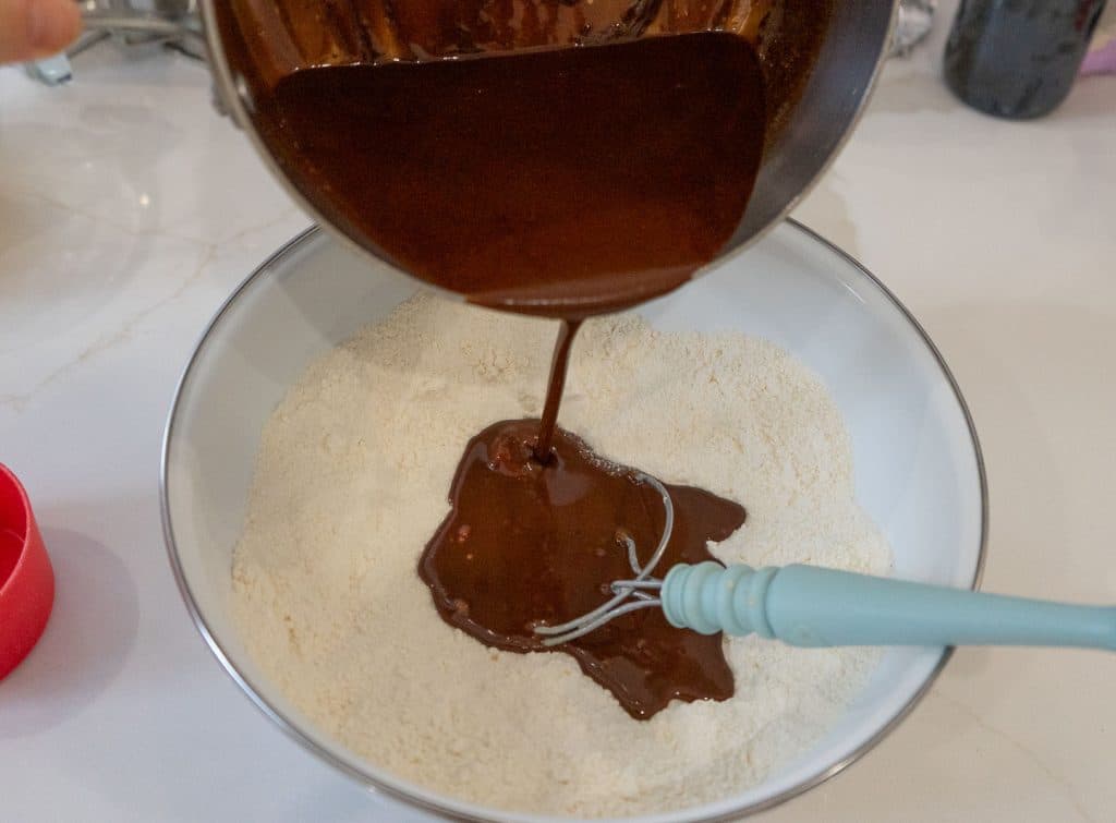 pouring melted chocolate butter into flour dry ingredients