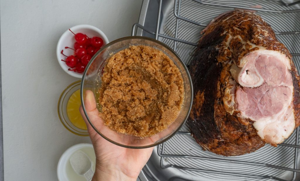 hand holding glass bowl of brown sugar glaze 