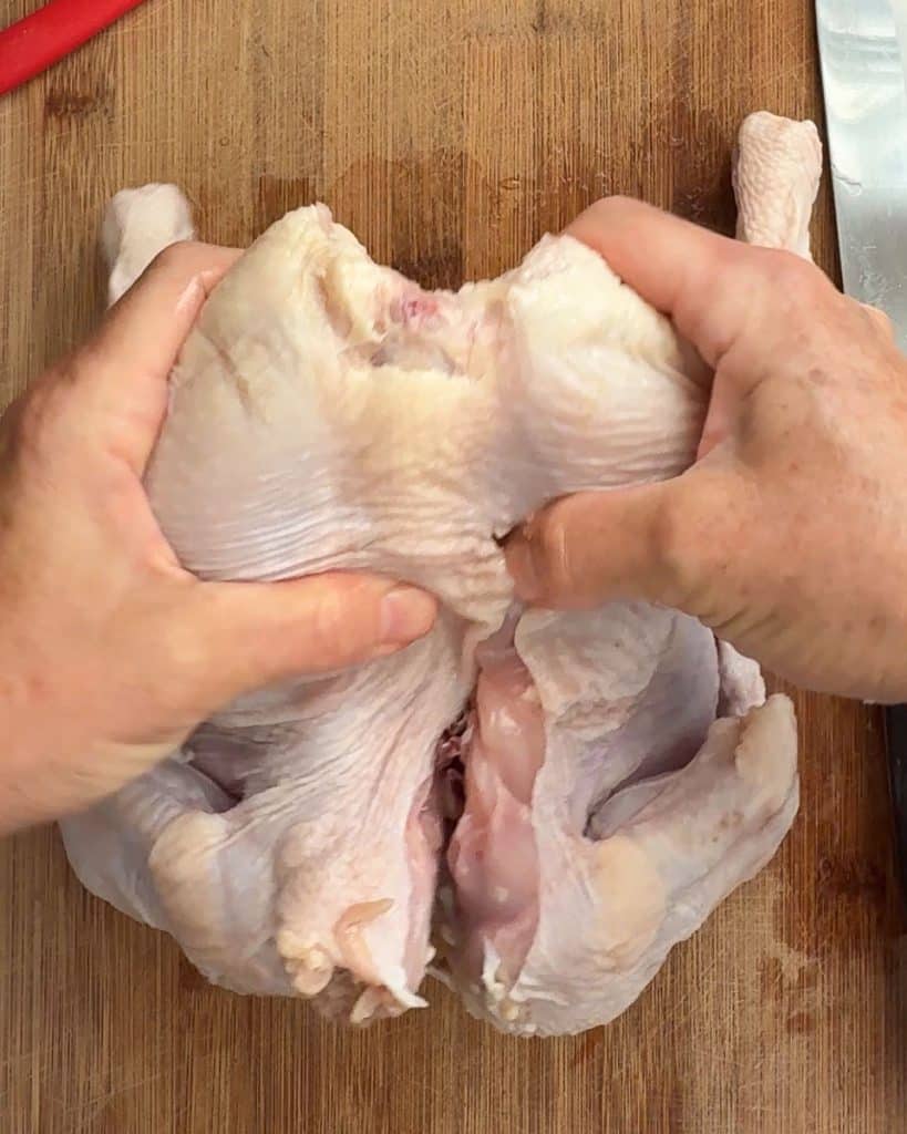cracking the back of the chicken before cutting along the backbone