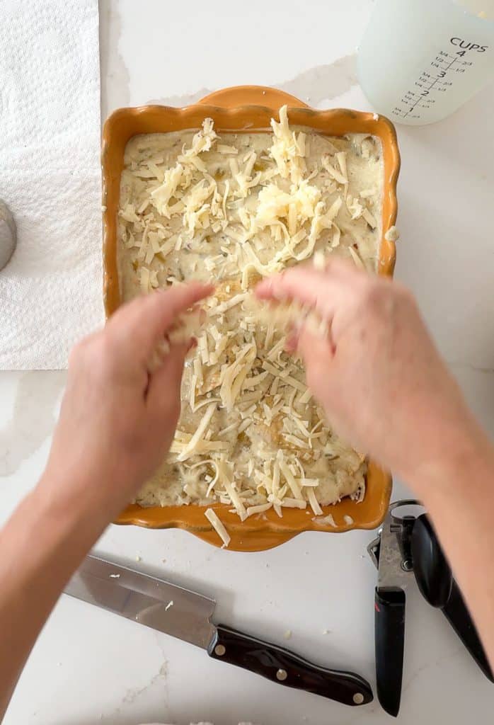 Ribbet collage the last layer of cheese to top of the enchilada bake. hands are spreading cheese over top of enchiladas