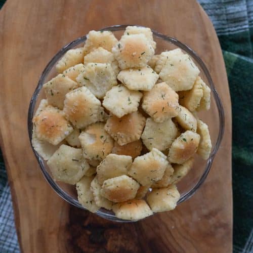 glass bowl with munchie crackers on a wood board