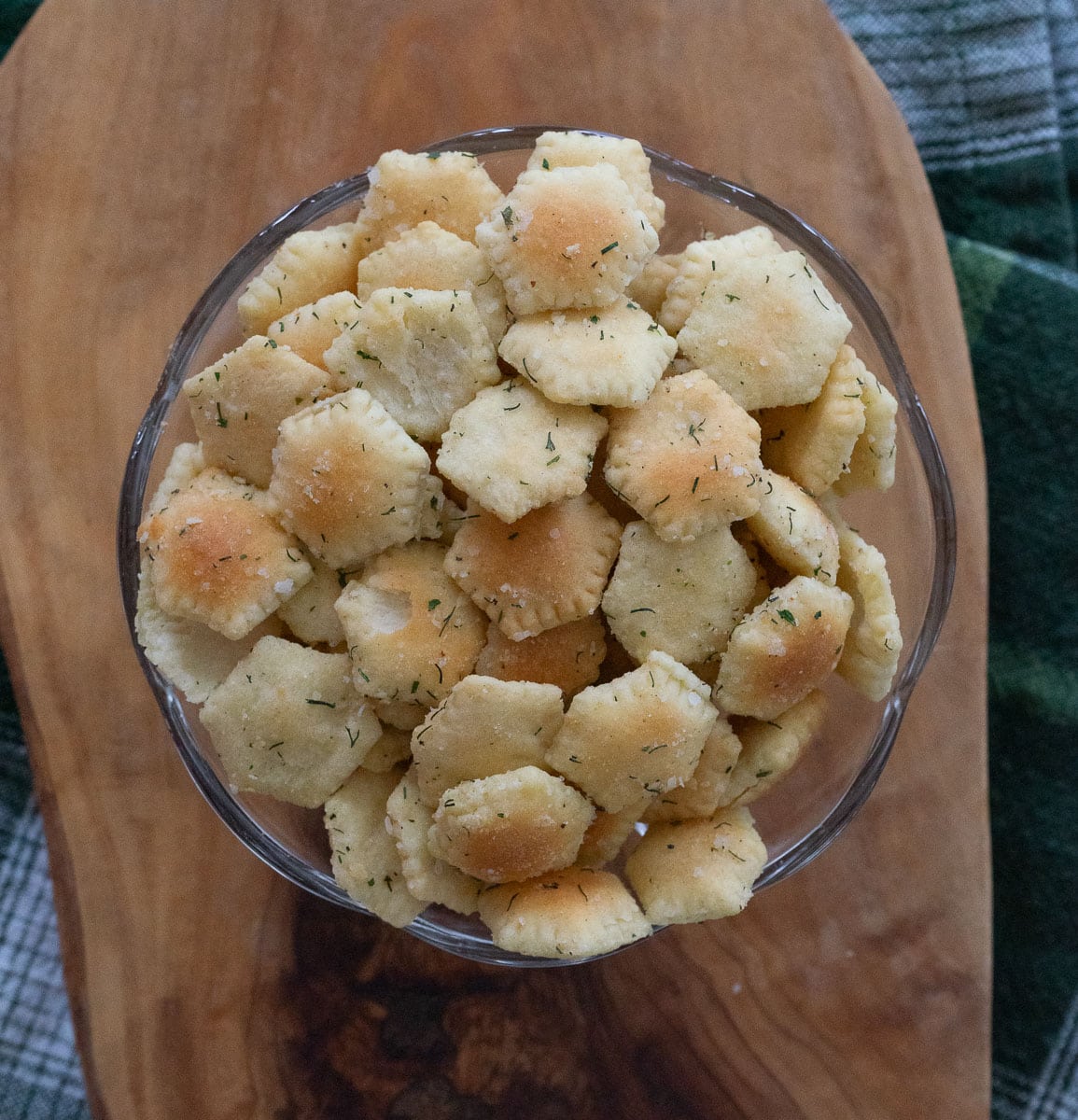 glass bowl with munchie crackers on a wood board