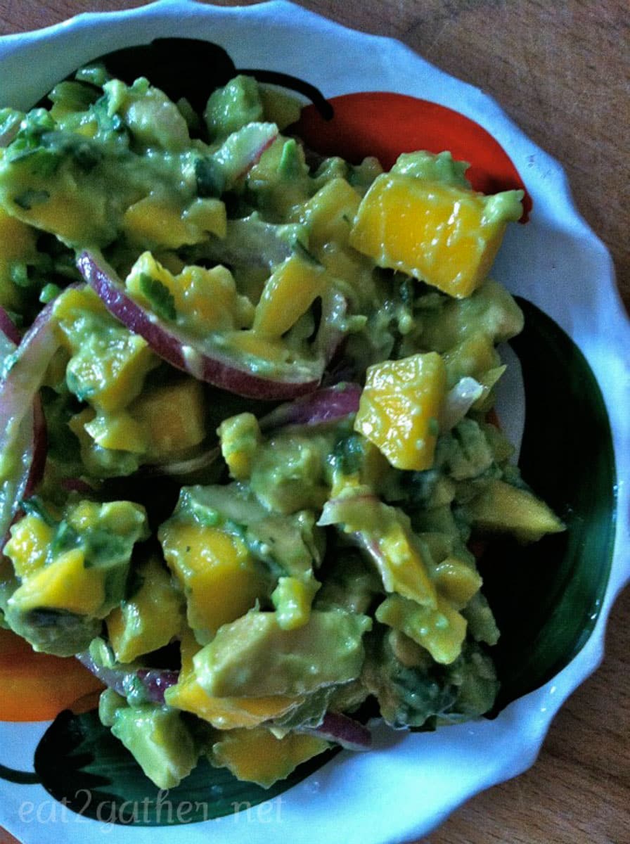 mango avocado salad in a small dish sitting on a wood table