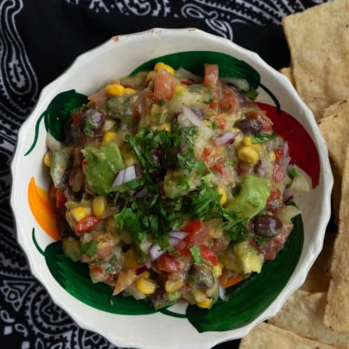 a dish of cowboy caviar with chips on the side on a black bandana