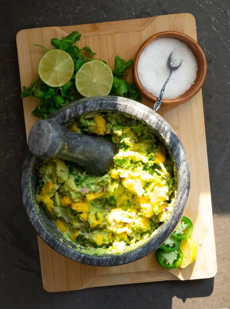 IMG_6622 stone dish of mango guacamole with fresh cilantro and lime with a dish of salt next to it