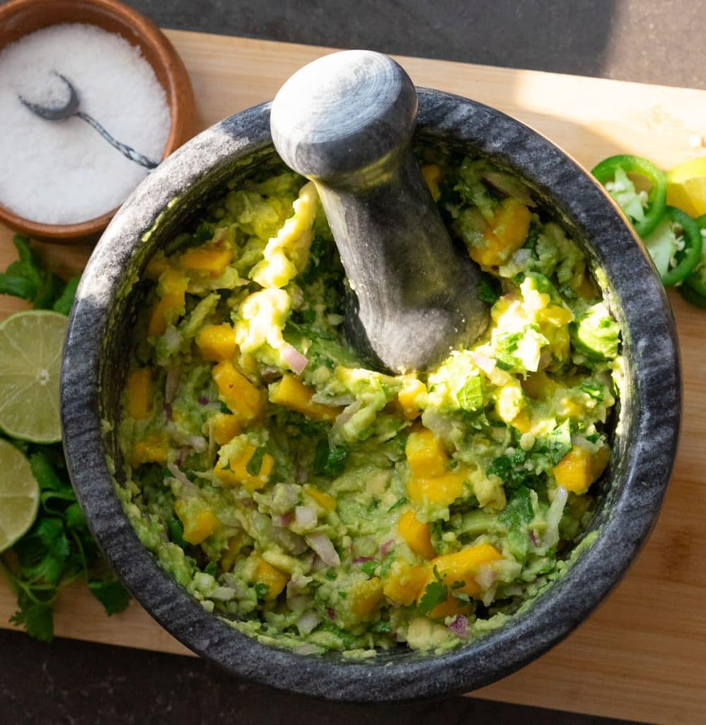 IMG_6628 stone dish of mango guacamole with fresh cilantro and lime with a dish of salt next to it
