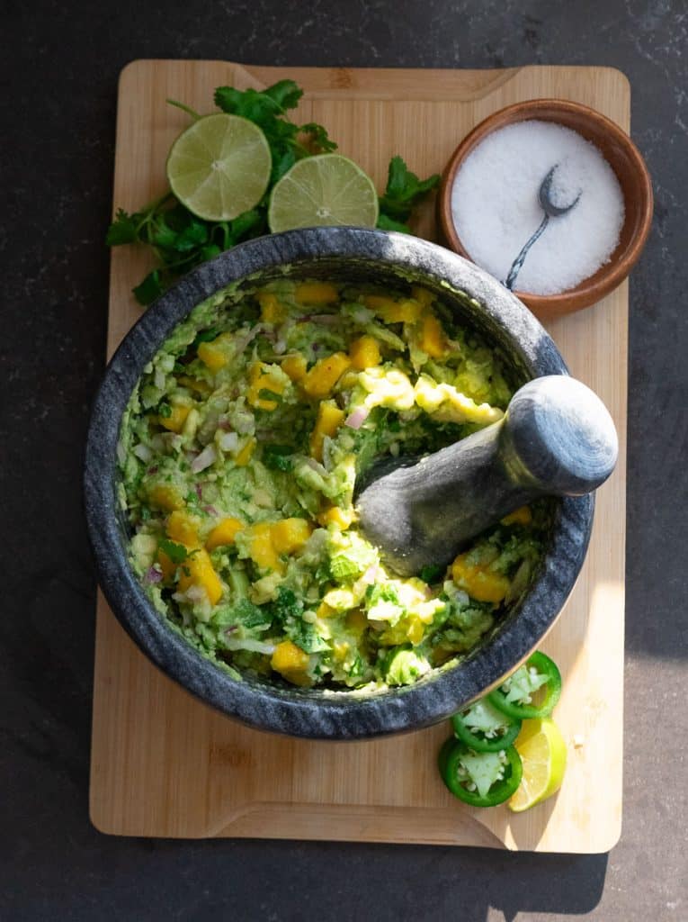 IMG_6620 stone dish with mango guacamole salad in it with fresh cilantro and lime with a dish of salt dispayed above the bowl