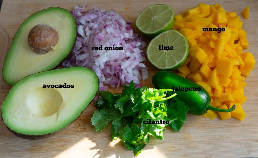 ingredients for mango guacamole on a wooden cutting board