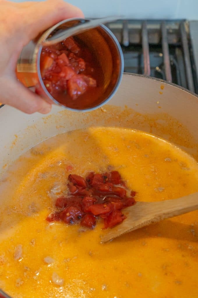 adding can of diced tomatoes to the pot