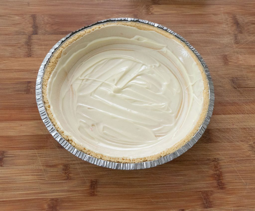 pie crust with white chocolate covering the entire crust pie crust is setting on a wood cutting board