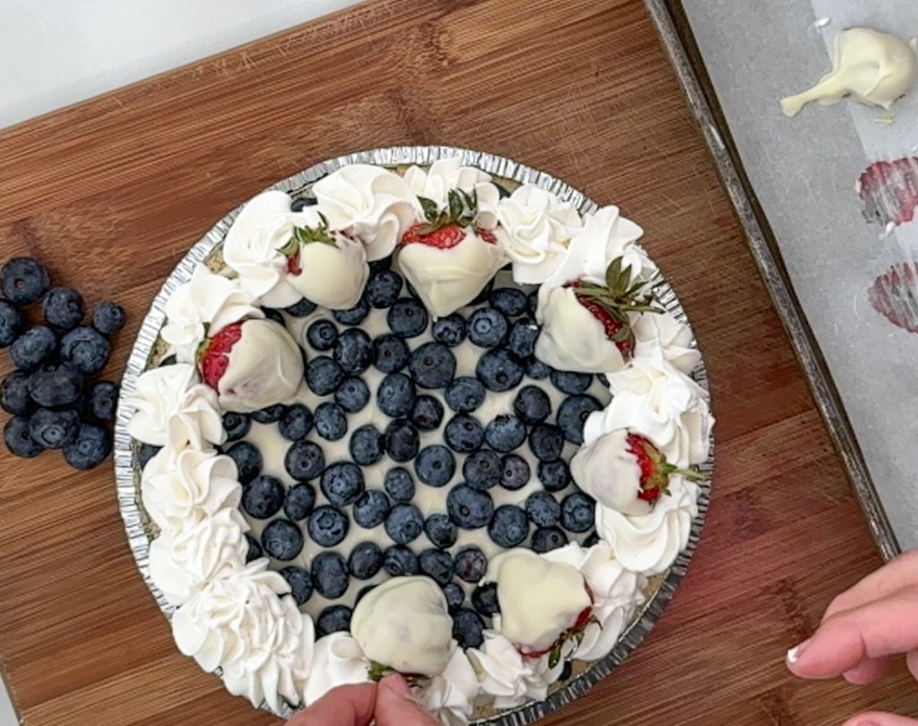 placing chocolate covered strawberries around the edge of the pie for garnish