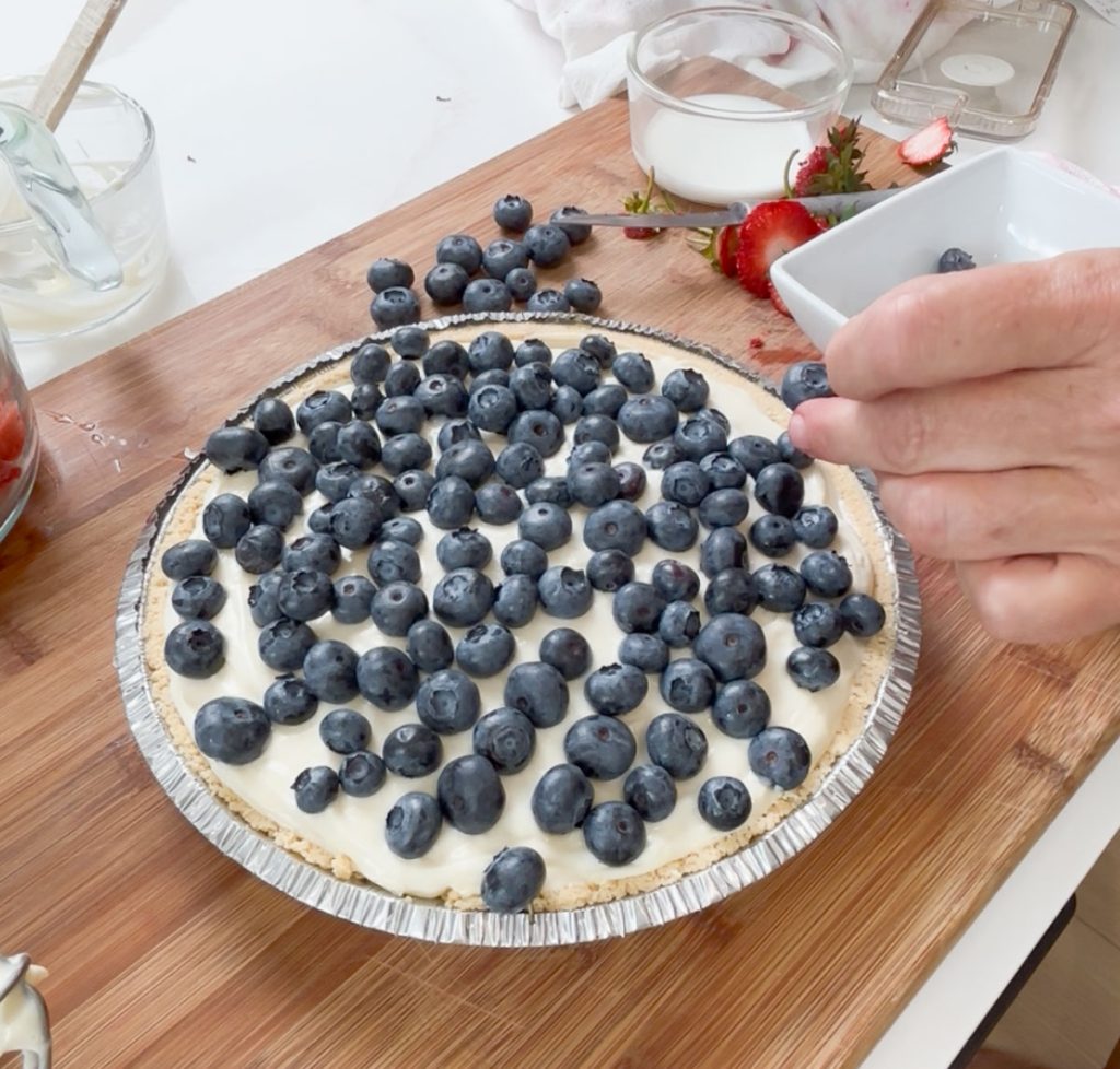 placing fresh blueberries over the cheesecake filling