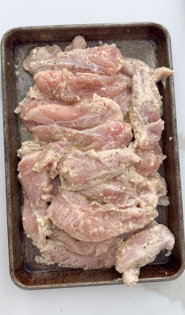 uncooked lemon pepper chicken on a baking sheet