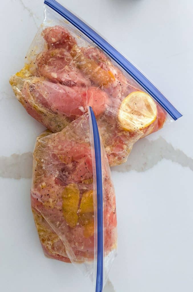 bags of chicken tenderloins in lemon marinade on a white countertop
