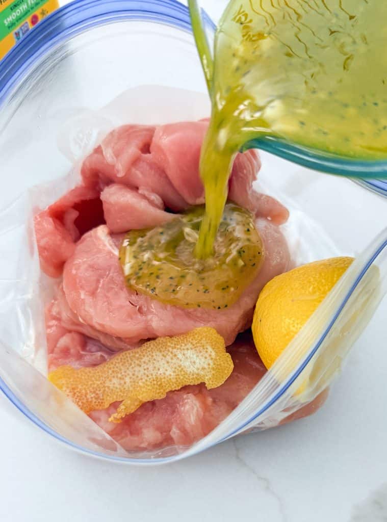 pouring marinade over the chicken tenders in zip-loc plastic bags