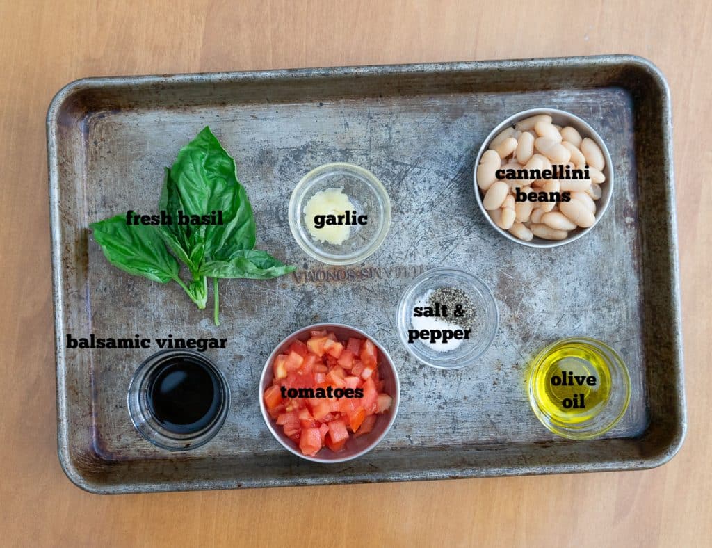 ingredients for bruschetta on a baking sheet on a wood countertop